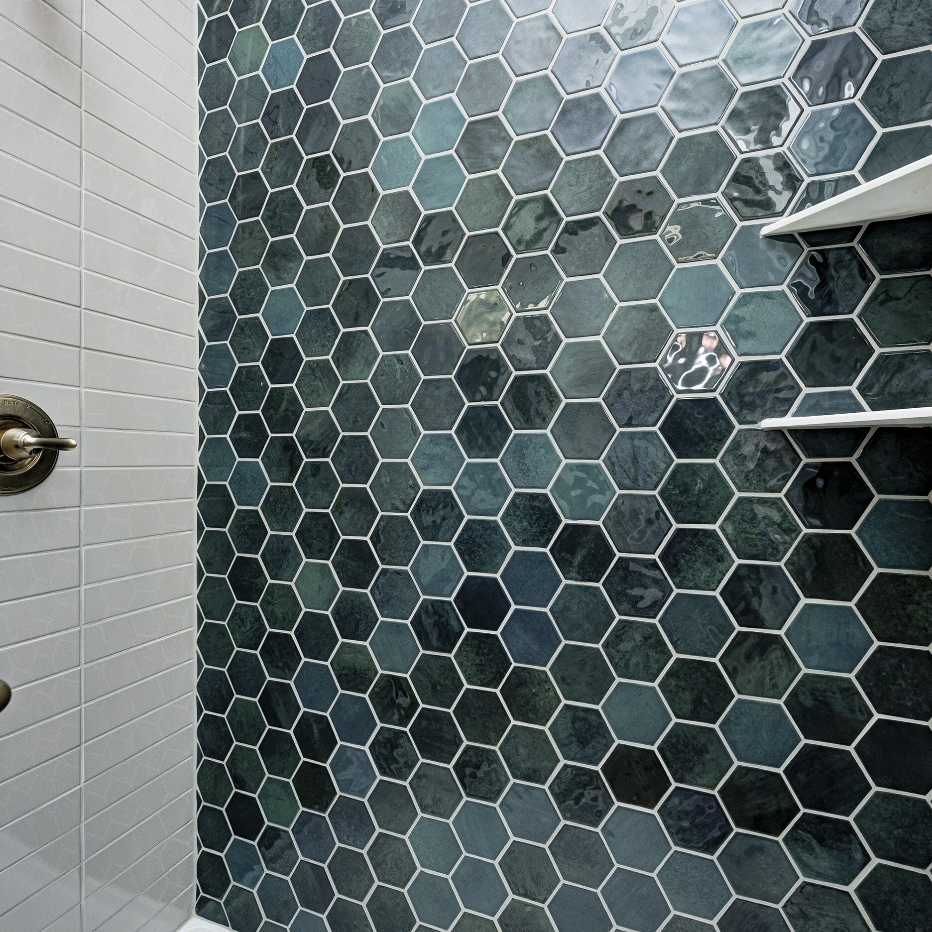 A blue tiled shower with a glass shelf.