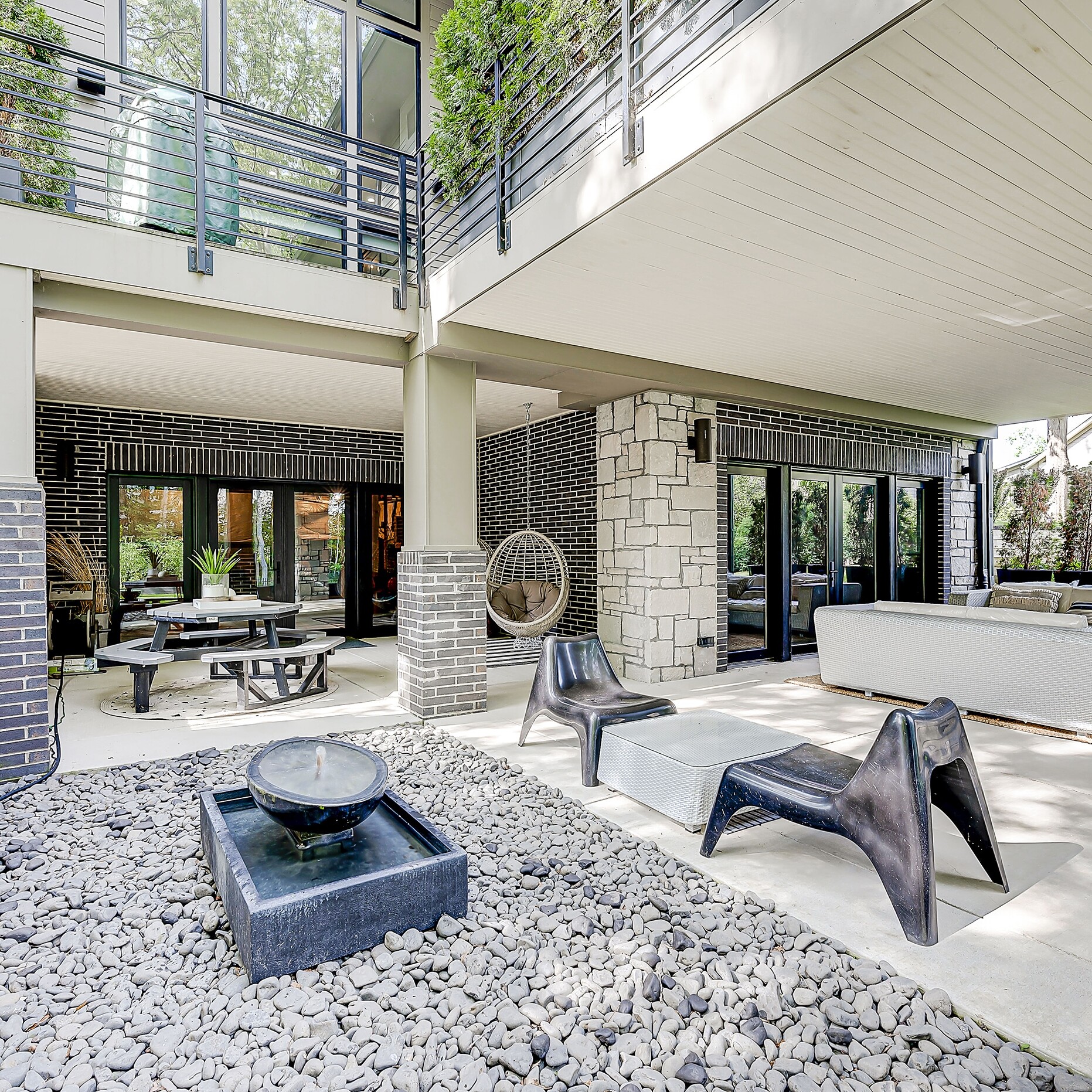 A modern backyard with a stone patio and a fire pit.