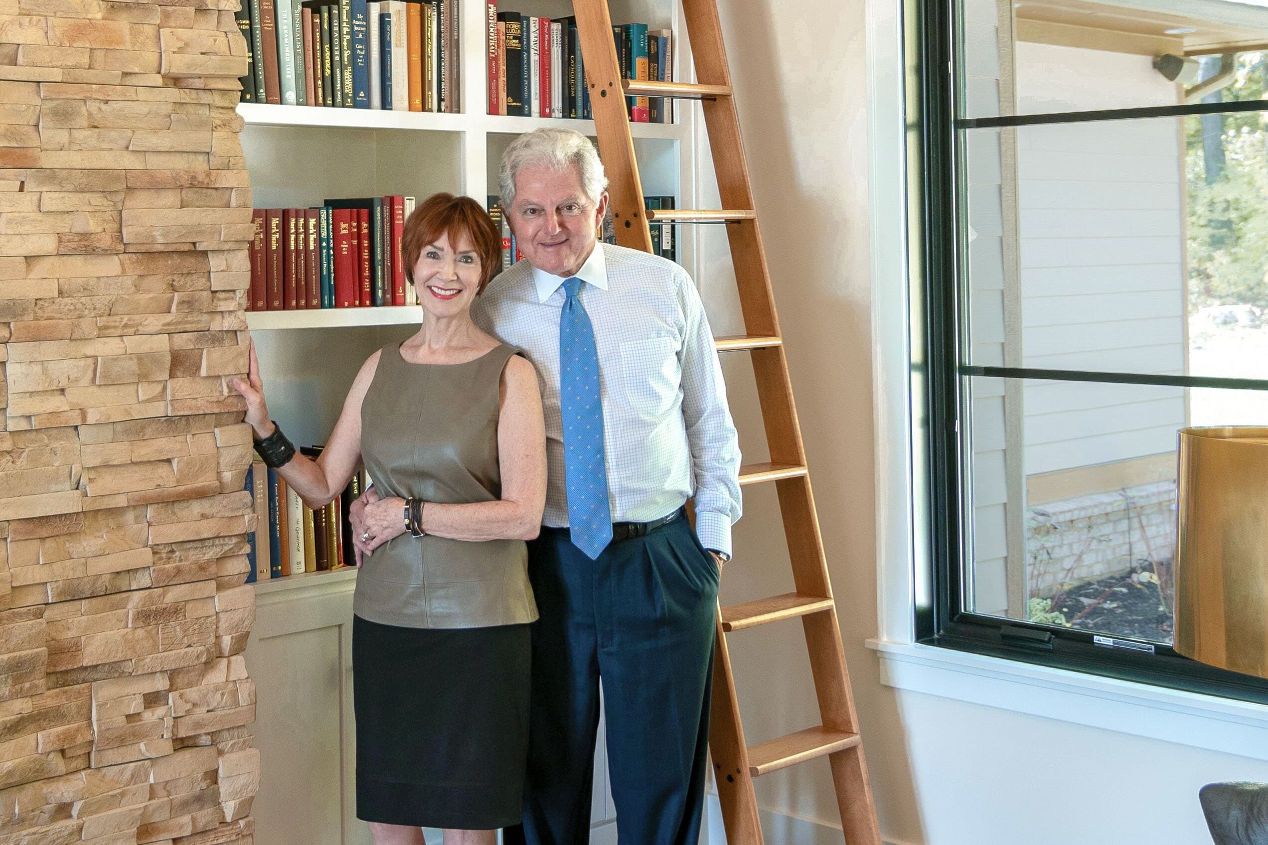A man and woman standing next to a bookcase.