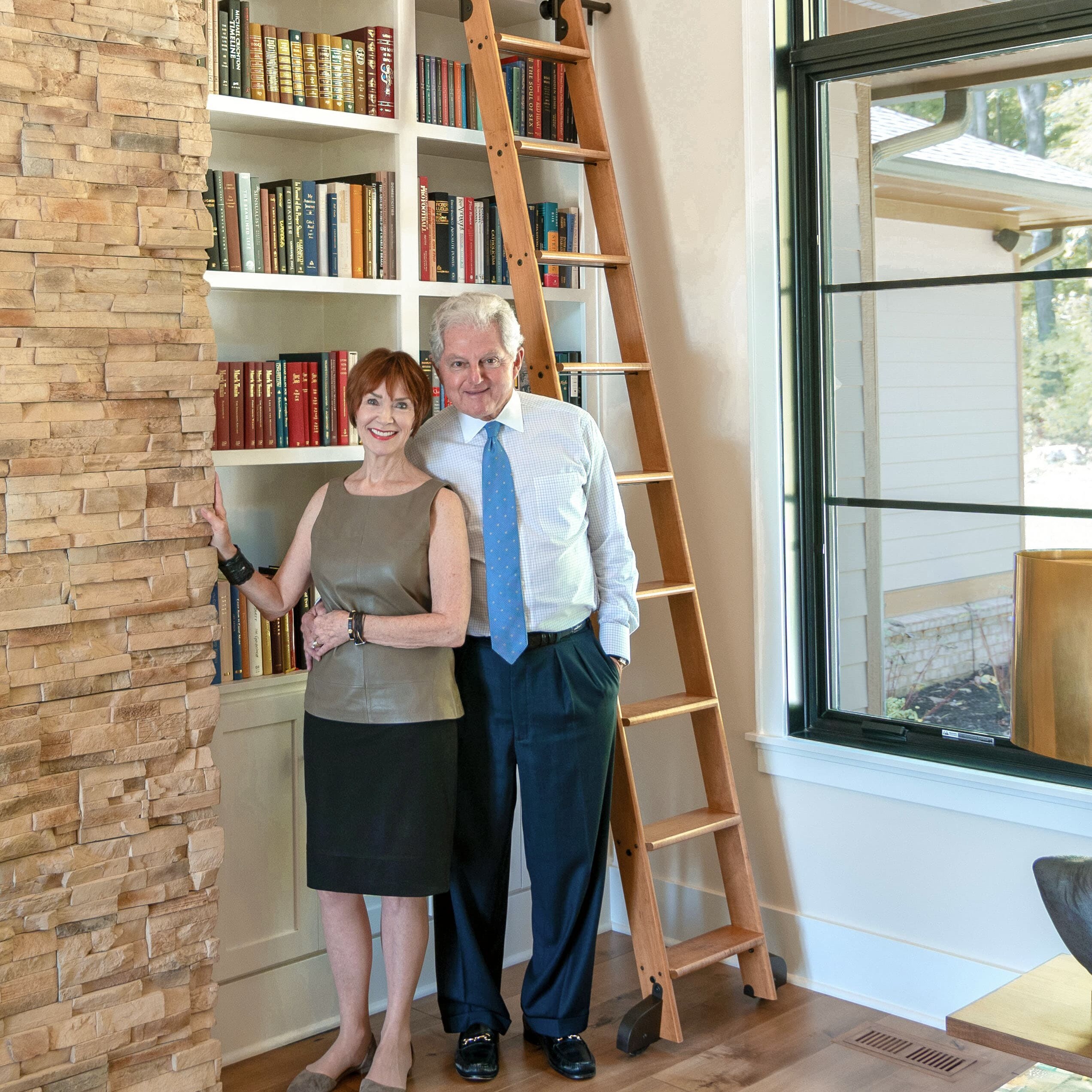A man and woman standing next to a bookcase.