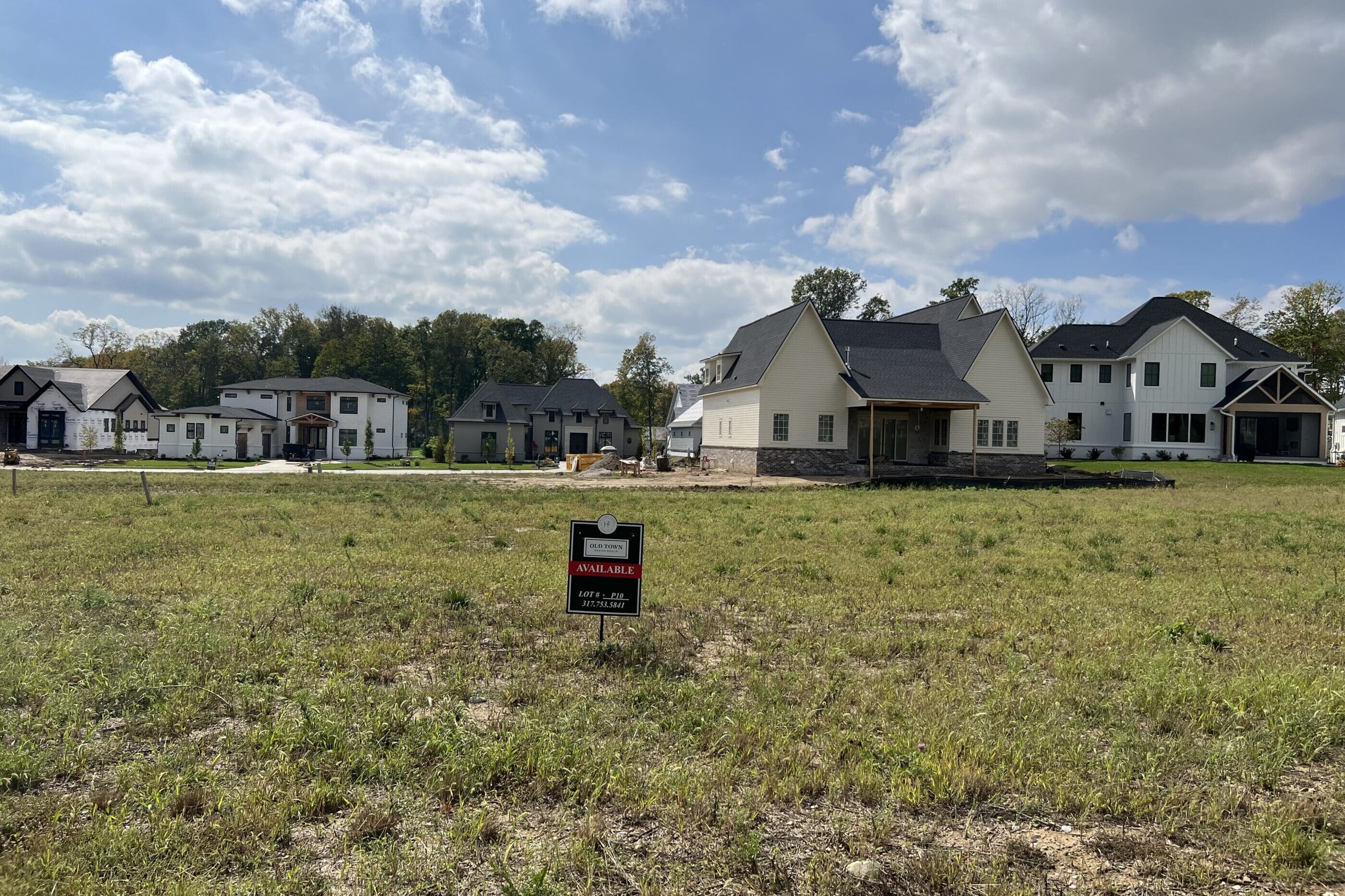 A field with houses and a sign in front of it, showcasing luxurious custom homes built by a top custom home builder in Indianapolis Indiana.