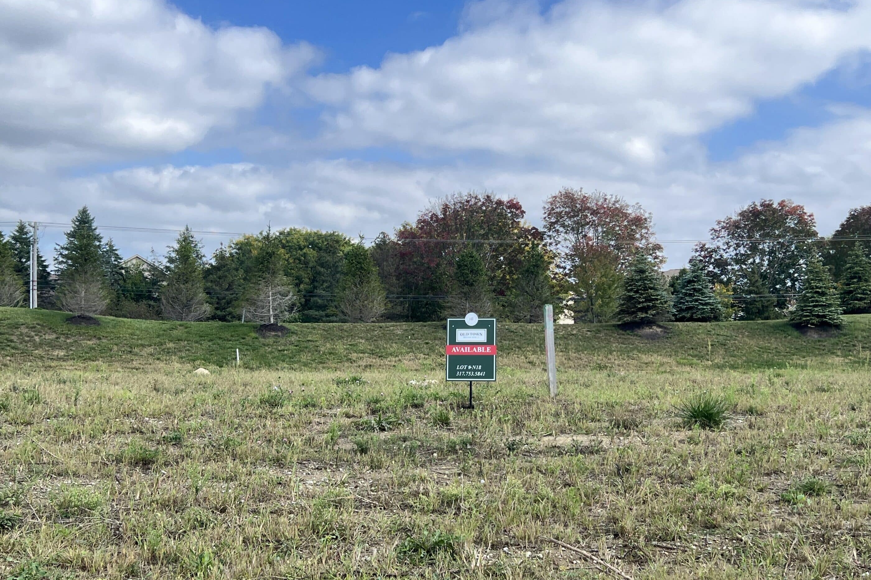 A field with a sign in the middle of it, surrounded by custom homes for sale in Carmel Indiana.