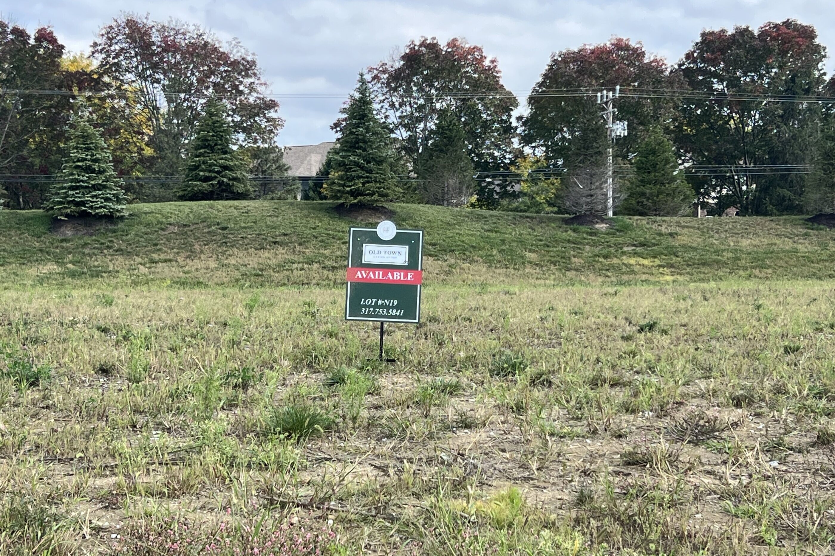 A vacant lot with a sign in the middle of a field, offering new homes for sale in Carmel Indiana.