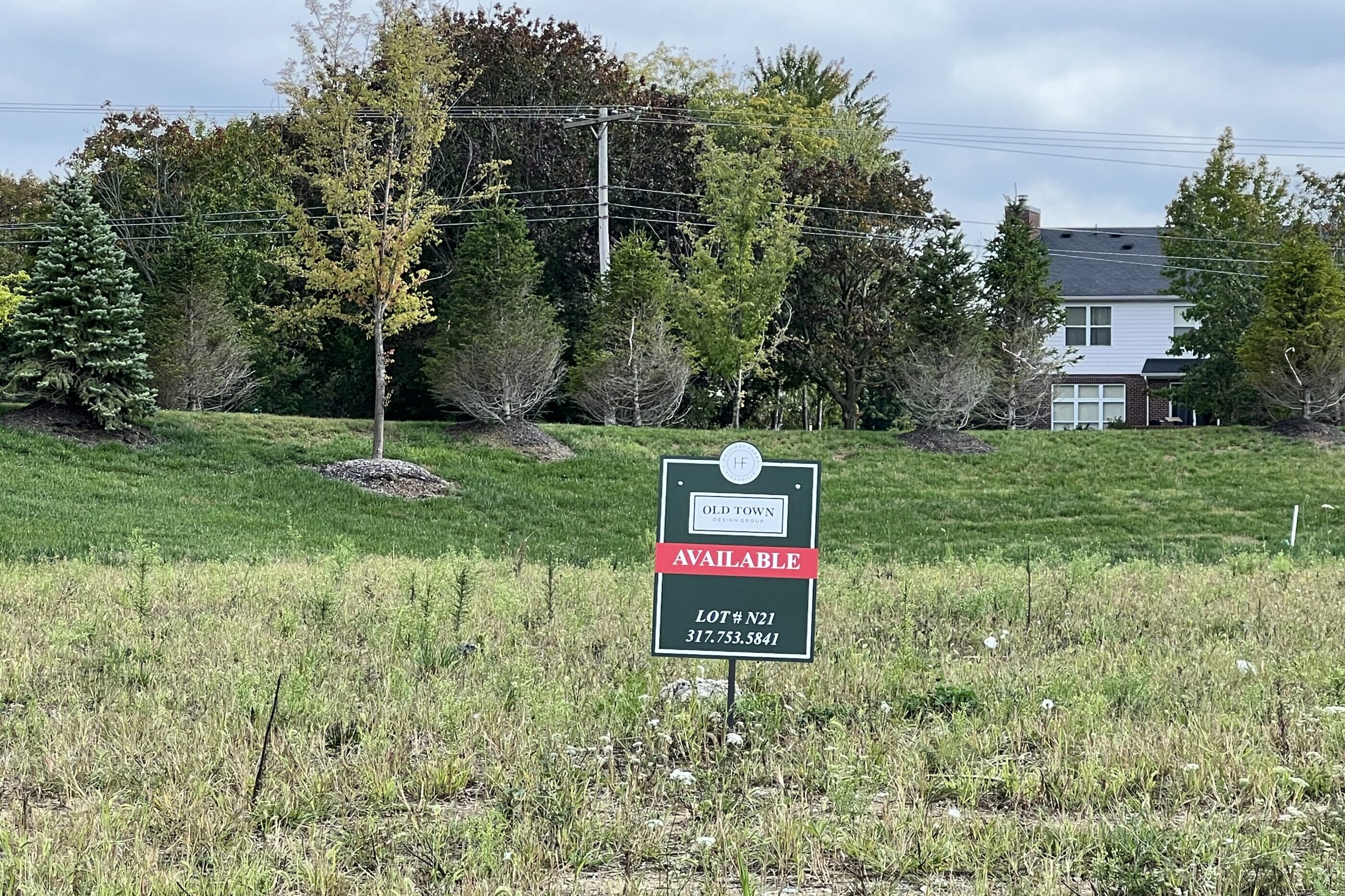 A field with a sign in the middle of it, surrounded by custom homes for sale in Carmel Indiana.