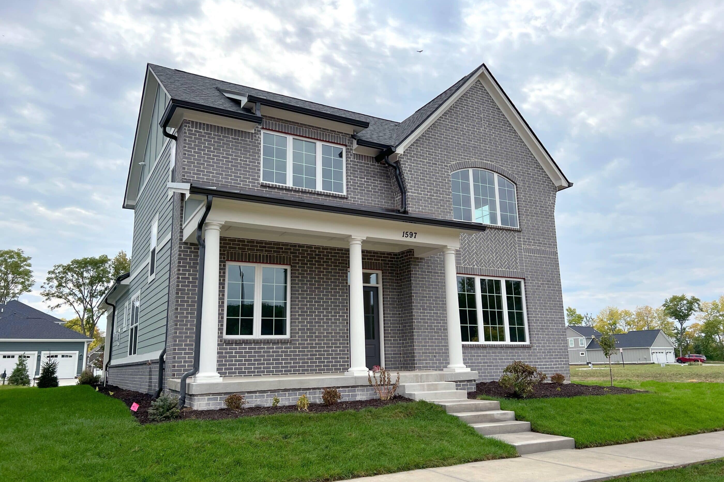 A luxury custom home in Westfield, Indiana, featuring a gray exterior with white trim and a charming front porch.