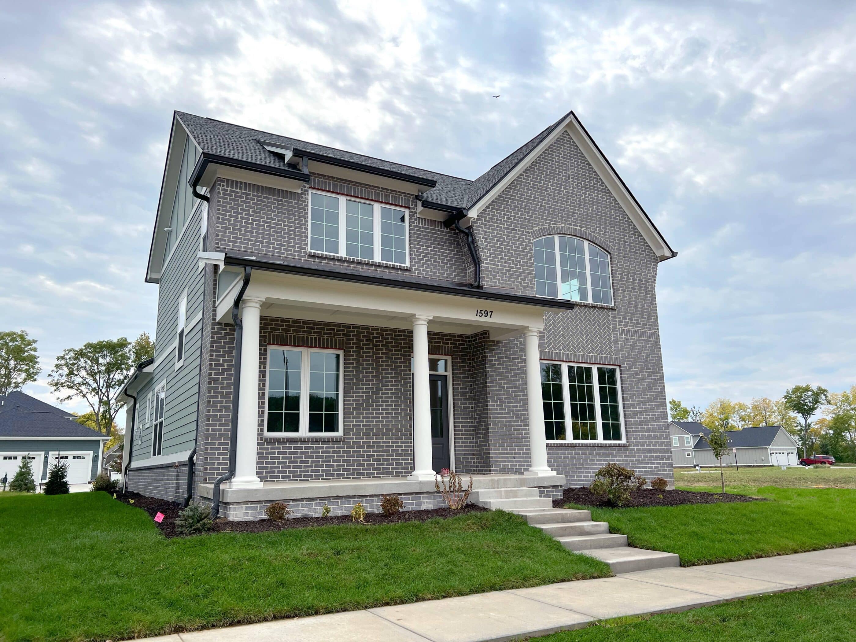 A luxury custom home in Westfield, Indiana, featuring a gray exterior with white trim and a charming front porch.