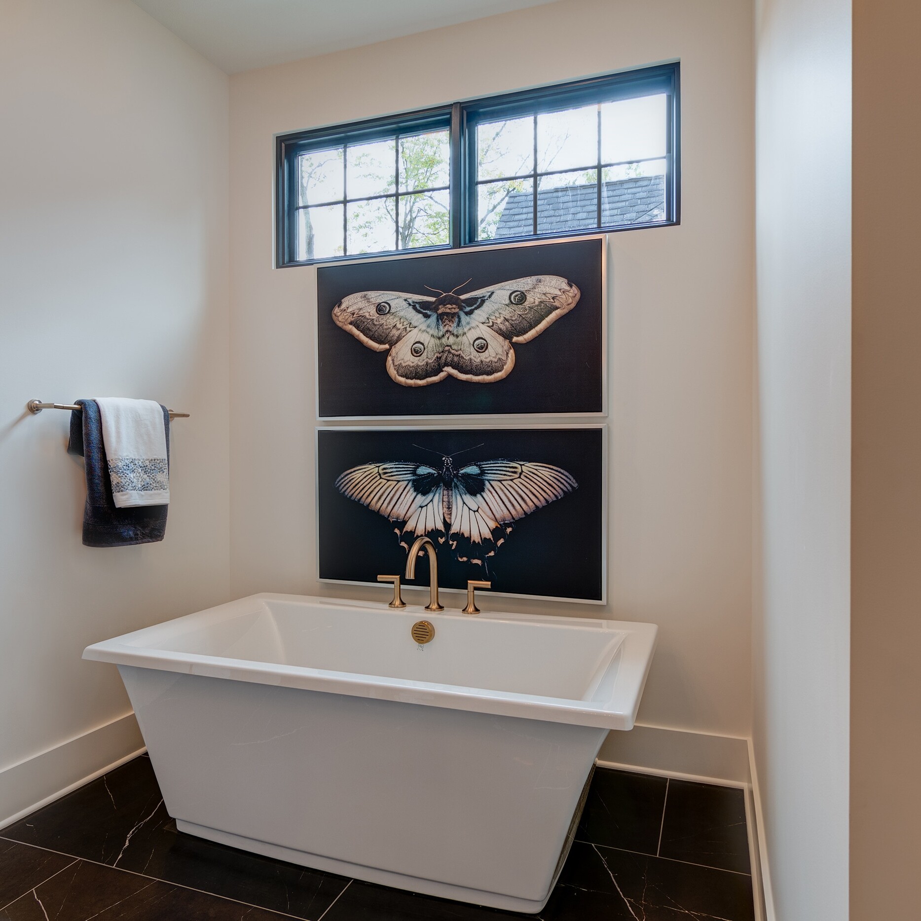 A bathroom with a large tub and two paintings on the wall.
