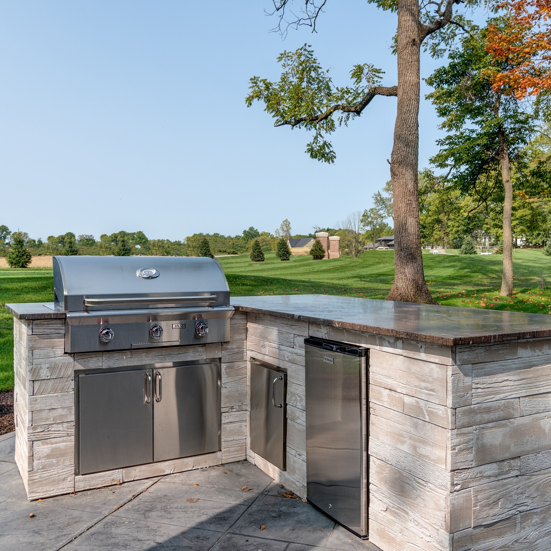 An outdoor kitchen with a grill and sink.