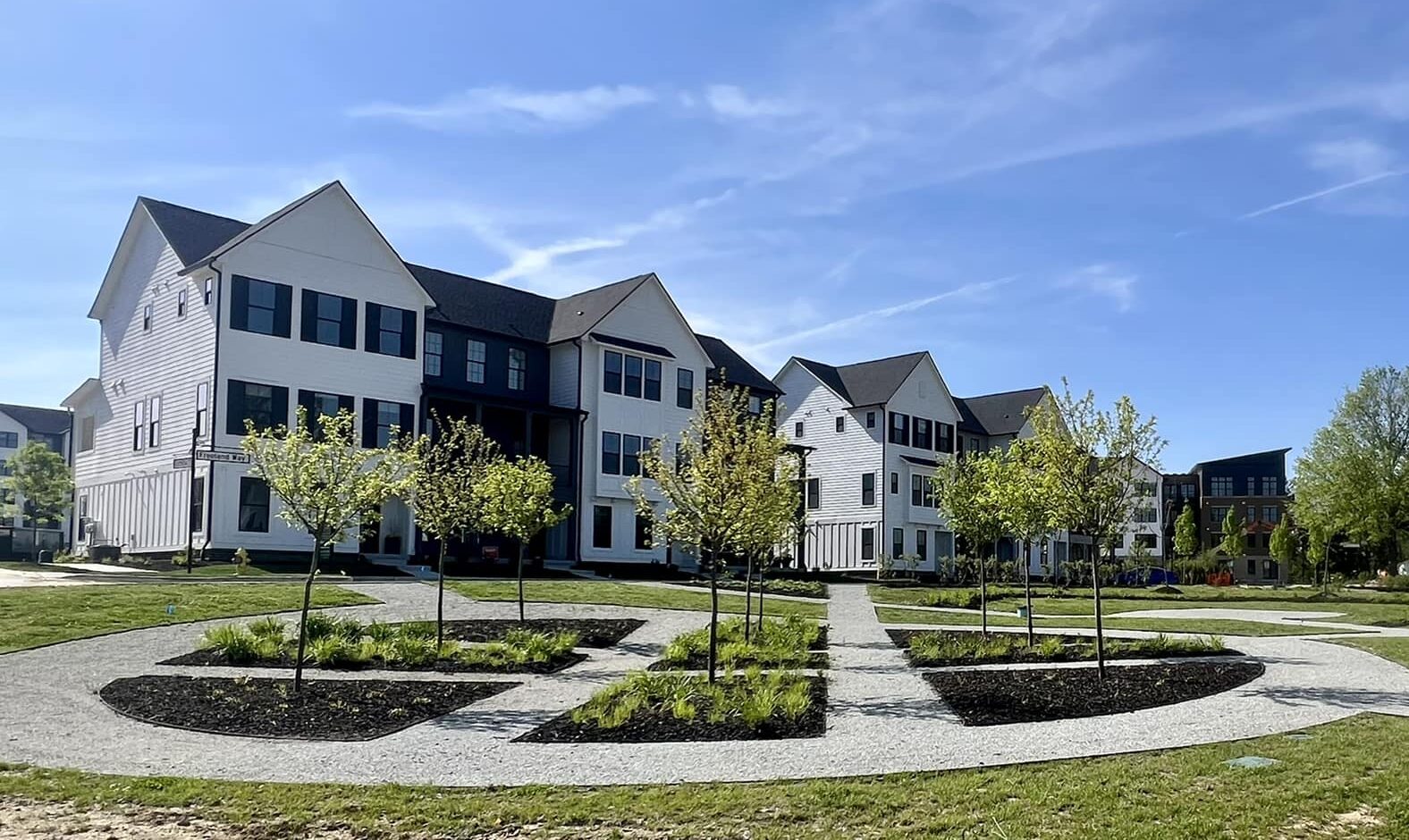 A newly constructed apartment complex with a walkway in front, featuring custom homes in Fishers and Westfield, Indiana.