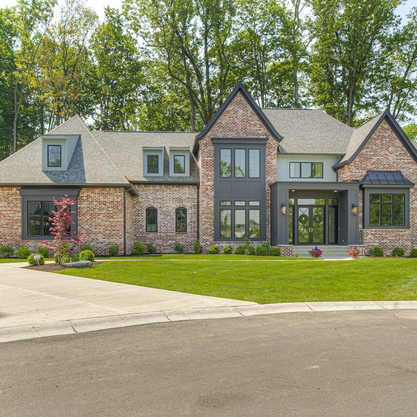 A large brick home with a driveway and trees.