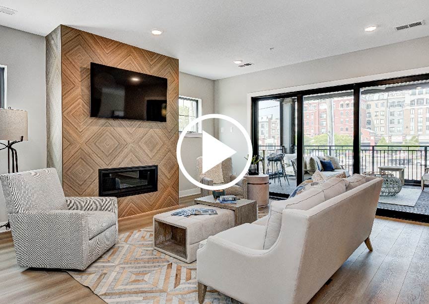 Take a virtual tour of a custom home featuring a cozy living room complete with a fireplace and balcony.