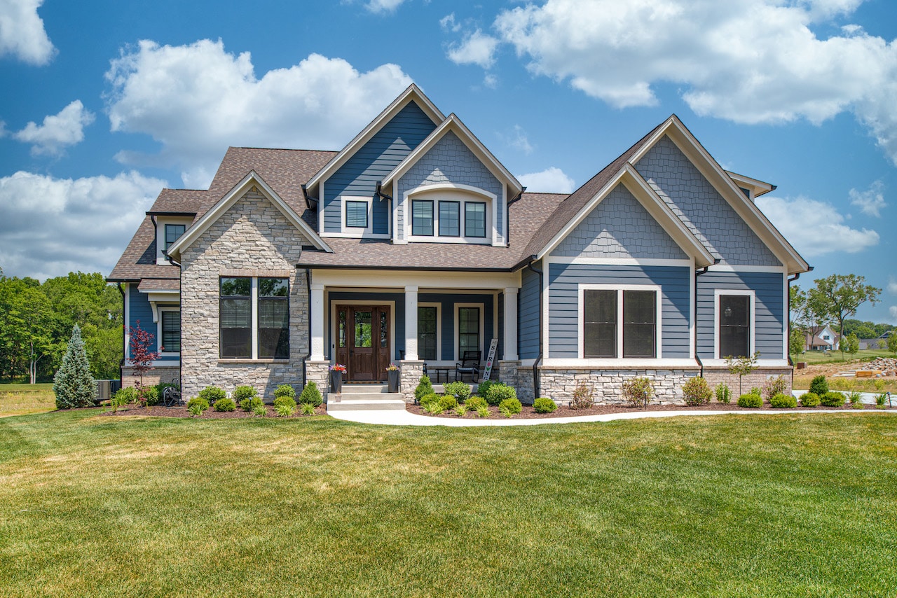 A custom home with blue siding and a grassy yard in Westfield, Indiana.