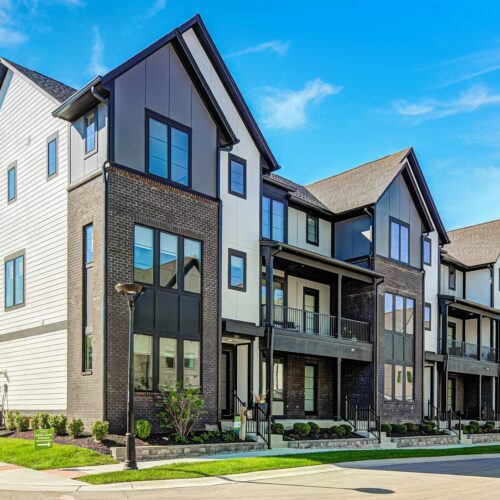 Corner view of a Midland South townhome building with brick, white and charcoal siding, steep gables and front porches