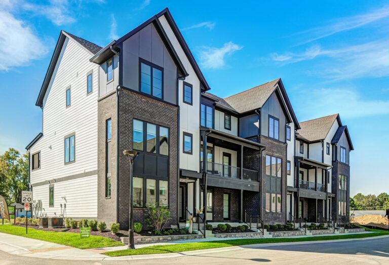 Corner view of a Midland South townhome building with brick, white and charcoal siding, steep gables and front porches