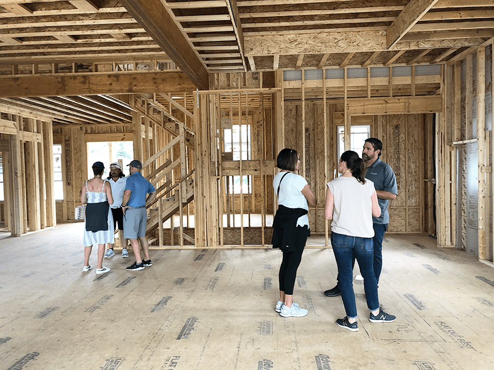 A group of luxury custom home builders standing in a room with wood framing.